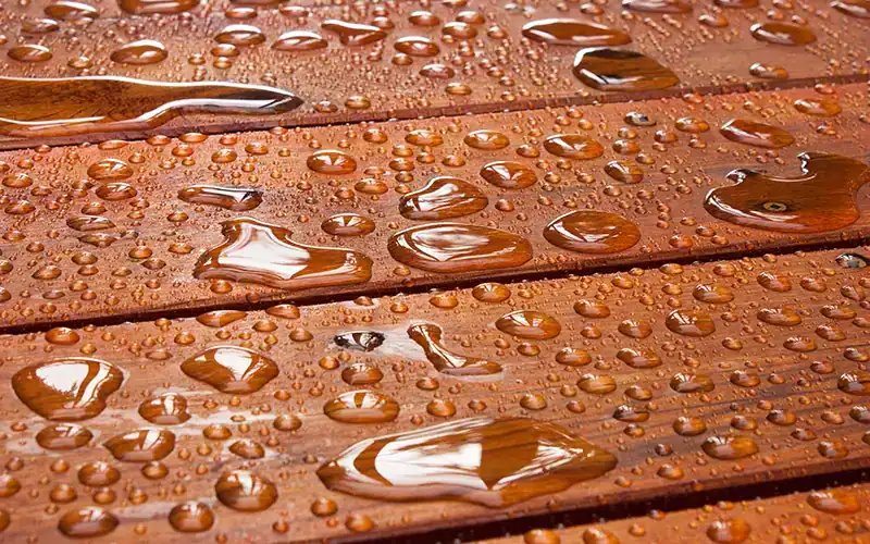 Waterdruppels op geïmpregneerd houten oppervlak, dat waterafstotend is gemaakt.