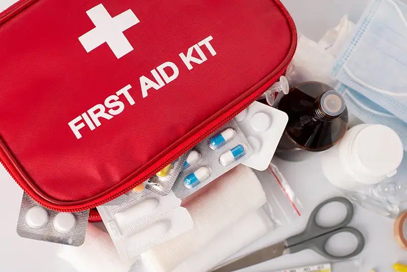 Open first aid kit with neatly arranged supplies such as adhesive bandages, dressings, scissors, gloves, and antiseptic wipes.