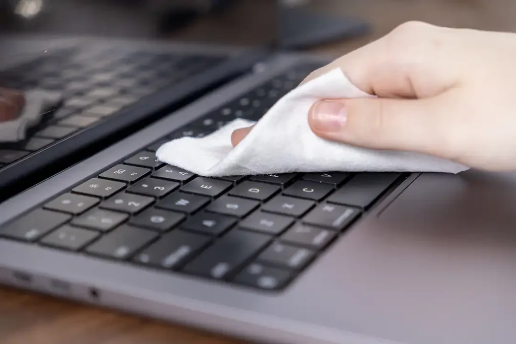 Image of someone cleaning their laptop with a cloth