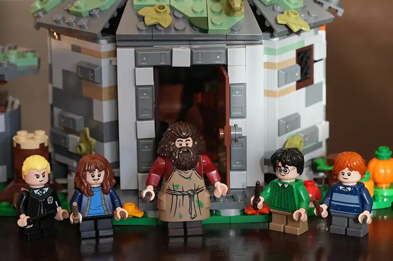 Lego figures of Harry Potter characters stand in front of a detailed Lego model of a house.